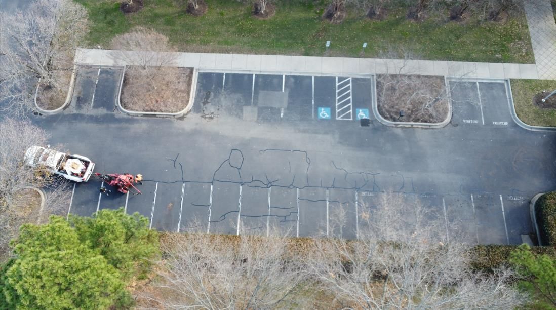 Aerial view of a paved parking lot with marked spaces, two accessible spots, and a truck parked on the left side.