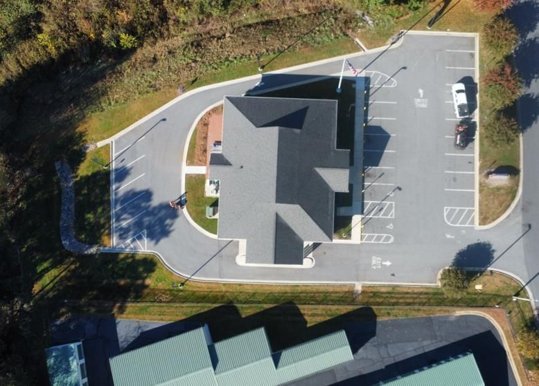 A freshly paved asphalt road at night, with a Lowe's store and parking lot illuminated in the background.