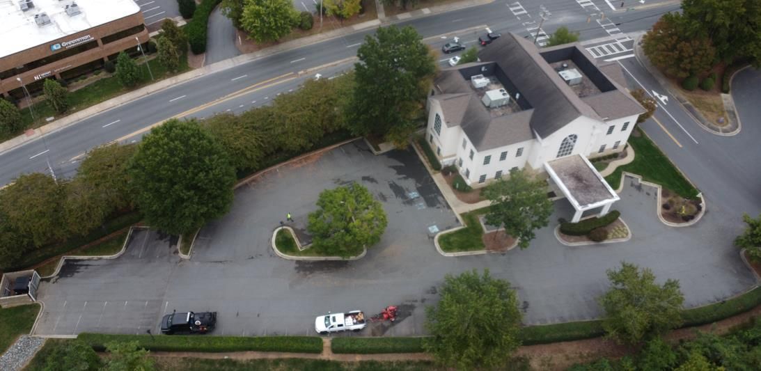 Aerial view of a paved parking lot with marked spaces, two accessible spots, and a truck parked on the left side.