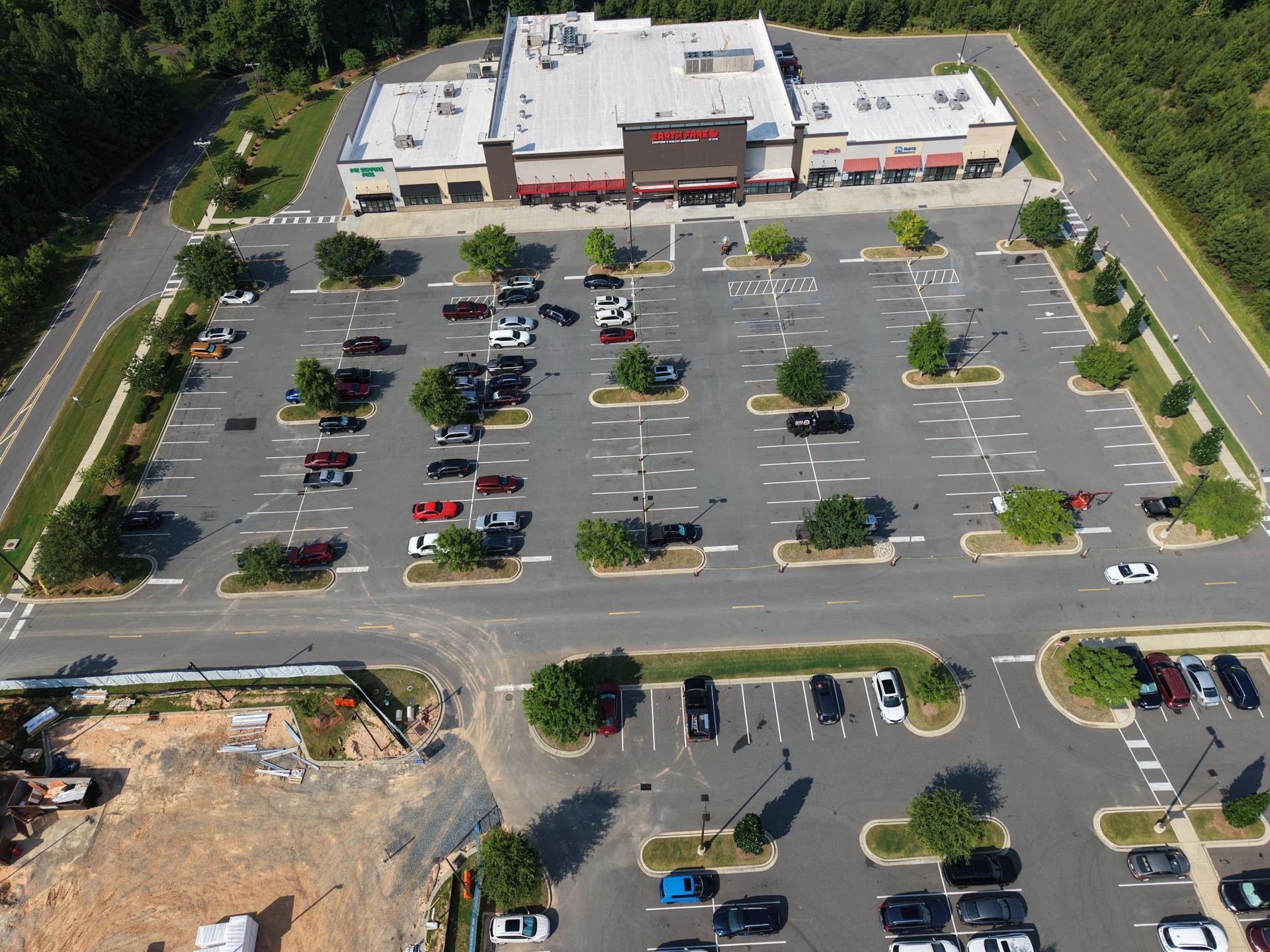 Aerial view of a rectangular warehouse building with a large parking lot and surrounding green space.
