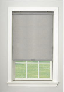 Gray roller blind partially covering a window with a white frame, overlooking a green lawn.