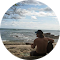 a man is sitting on the beach looking at the ocean .