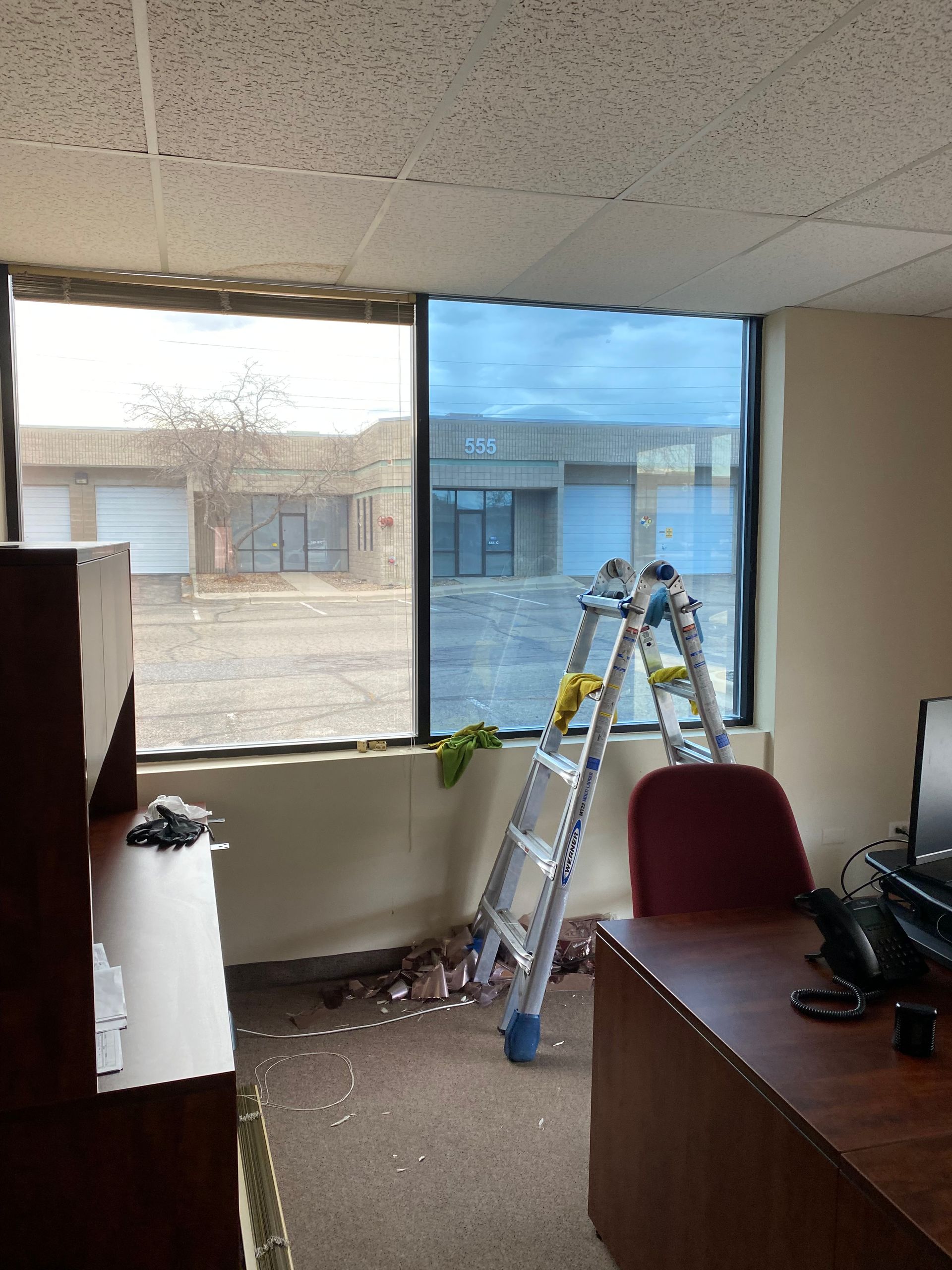 A ladder is sitting in front of a window in an office.