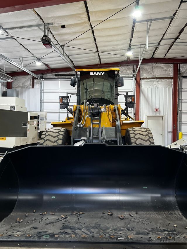 A bulldozer is parked in a garage with a large black bucket.