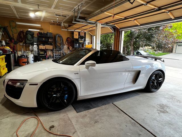 A white sports car is parked in a garage.