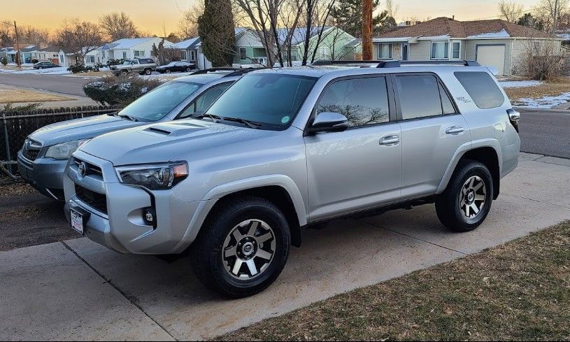 two silver toyota 4runner suvs are parked next to each other in a driveway .