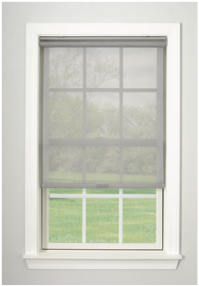 Gray roller shade on a white-framed window, partially covering a view of grass and trees.