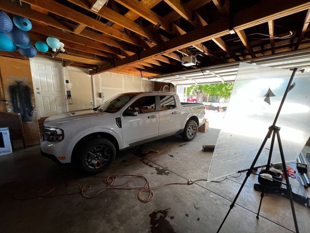 A white truck is parked in a garage next to a tripod.