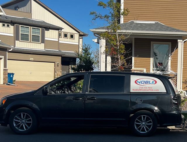 A black van is parked in front of a house.