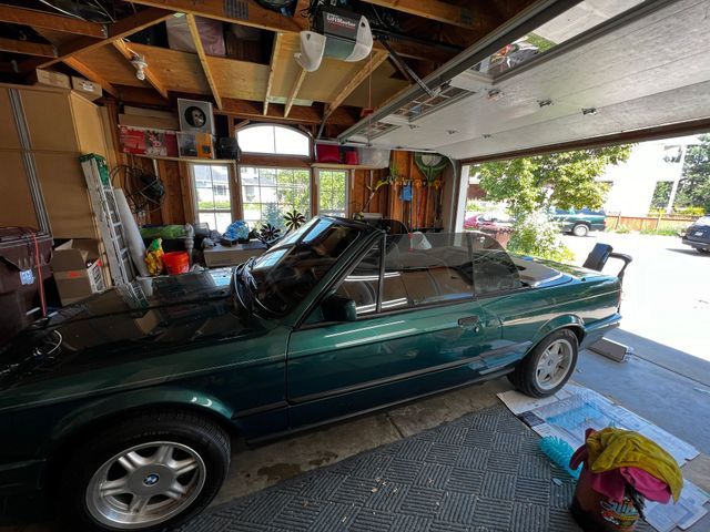 A green car is parked in a garage with the door open.