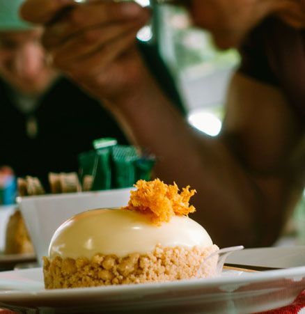 Een close-up van een dessert op een bord met een persoon op de achtergrond