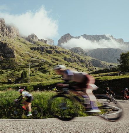 Een groep mensen fietst over een weg met bergen op de achtergrond