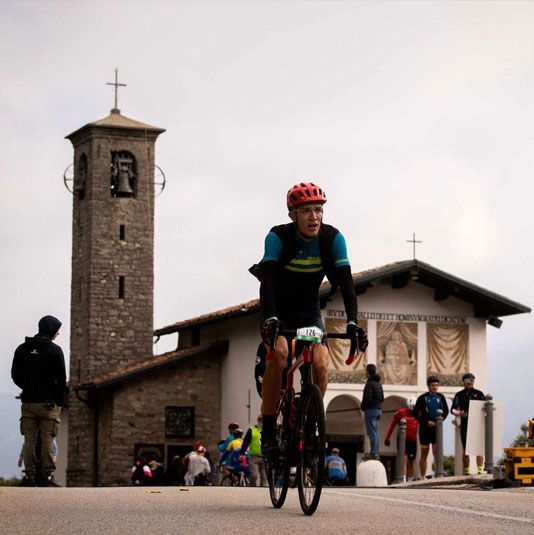 Voor een kerk fietst een man met een helm