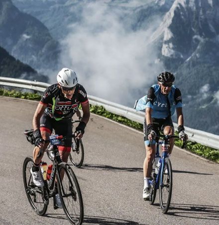 Twee fietsers rijden over een weg met bergen op de achtergrond