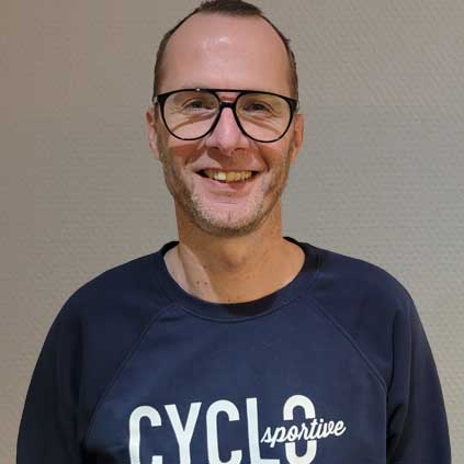 Een man met een bril en een blauw shirt met het woord cyclus erop.