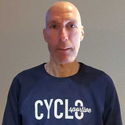 Een kale man, gekleed in een blauw sweatshirt met het woord cyclus erop.
