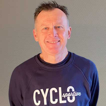 Een man in een blauw sweatshirt met het woord cyclus erop lacht naar de camera.