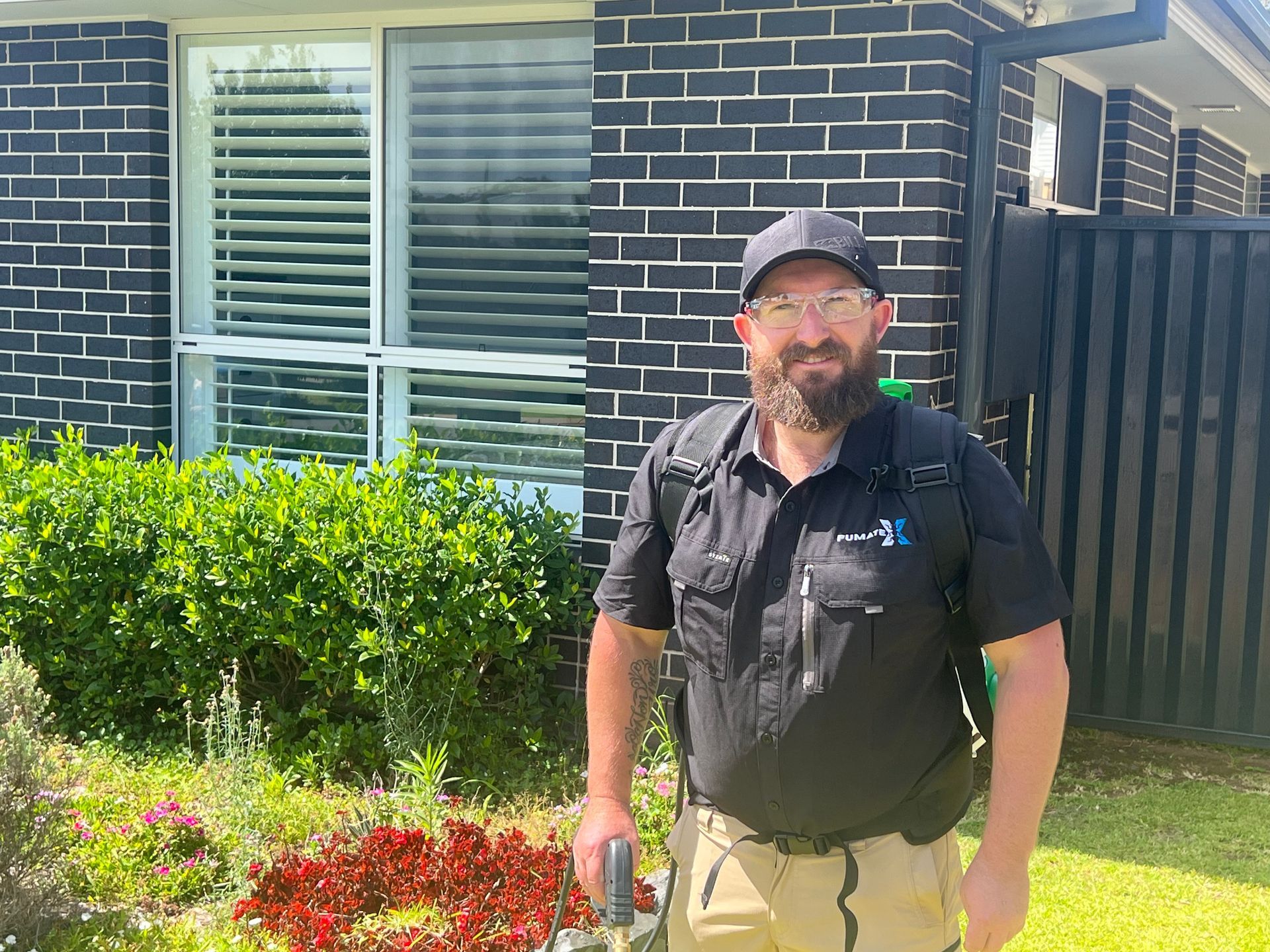 Man With Backpack Sprayer Stands in Front of a House — FUMATEX In Port Macquarie, NSW