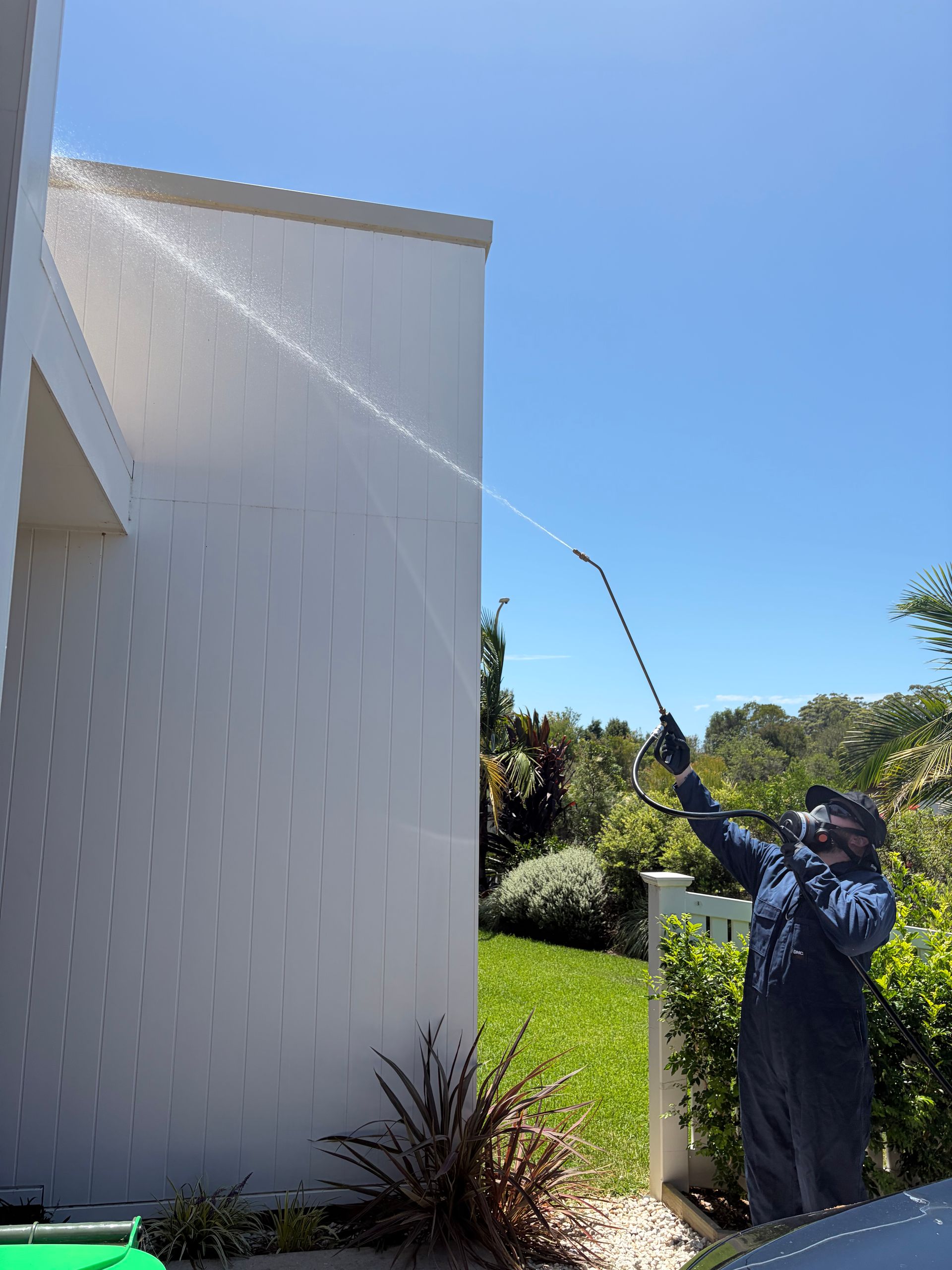 Pest Control Worker Spraying a Garden Near a Brick Wall and Fence — FUMATEX In Port Macquarie, NSW