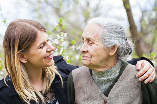 A young woman is hugging an older woman in a park.