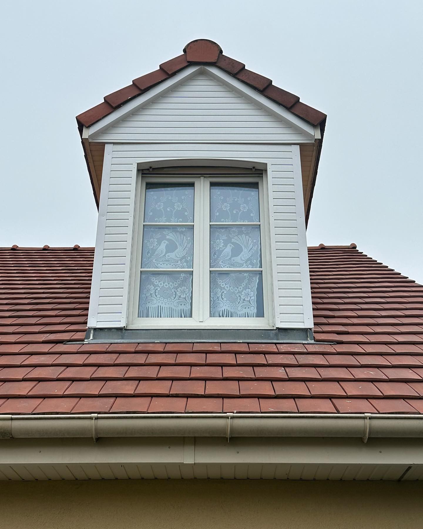 Balle de tennis et raquette sur un court en terre battue, projetant une ombre.