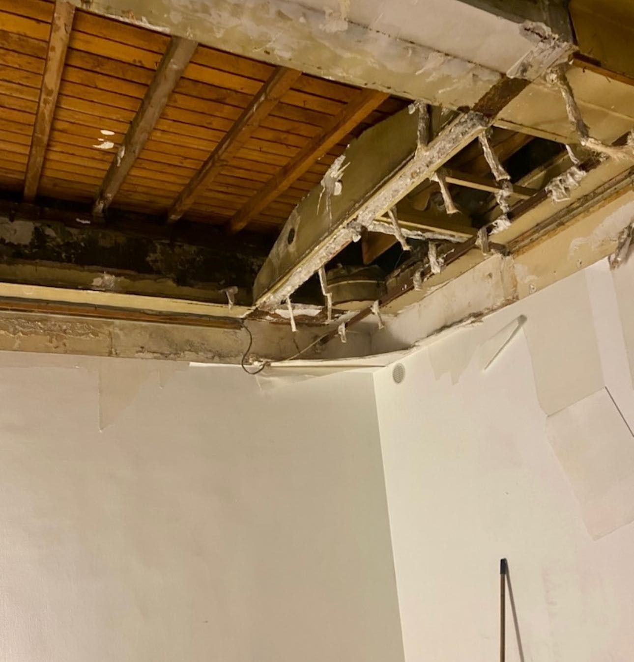 Un camion orange équipé d'une grue soulève des palettes de briques devant une maison.