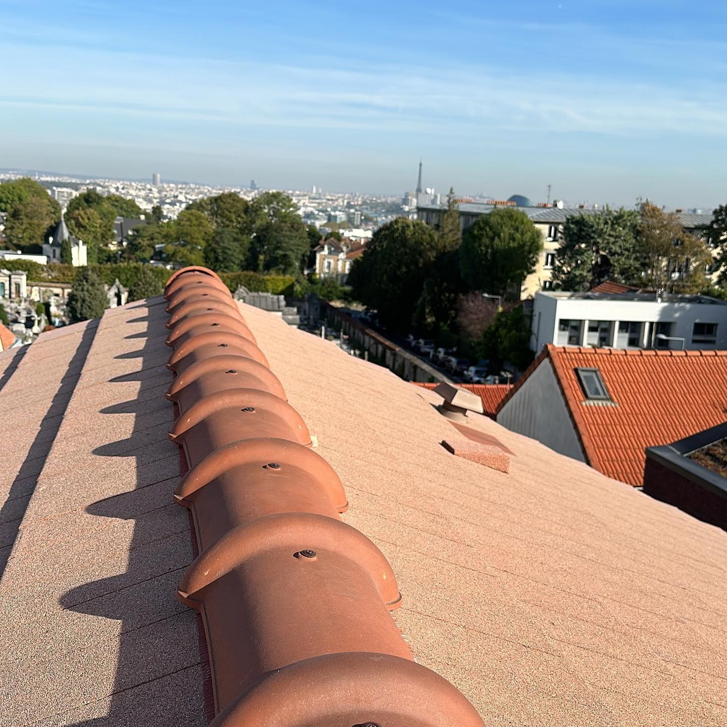 Puits de lumière sur un toit en bardeaux. Des bardeaux gris entourent une fenêtre rectangulaire aux encadrements foncés.