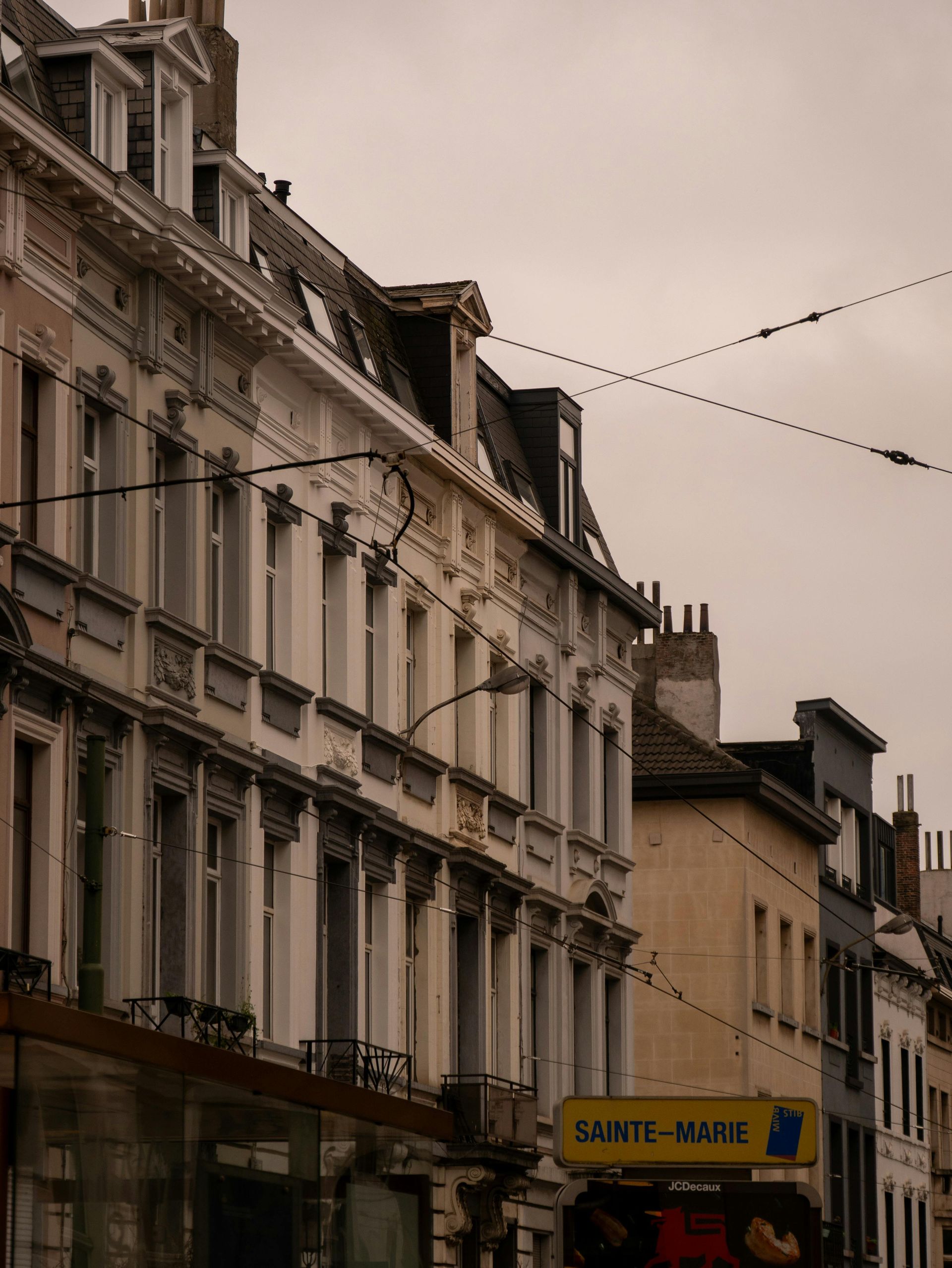 Cuisine moderne avec placards bleus et blancs, îlot central blanc, chaises orange et électroménager.