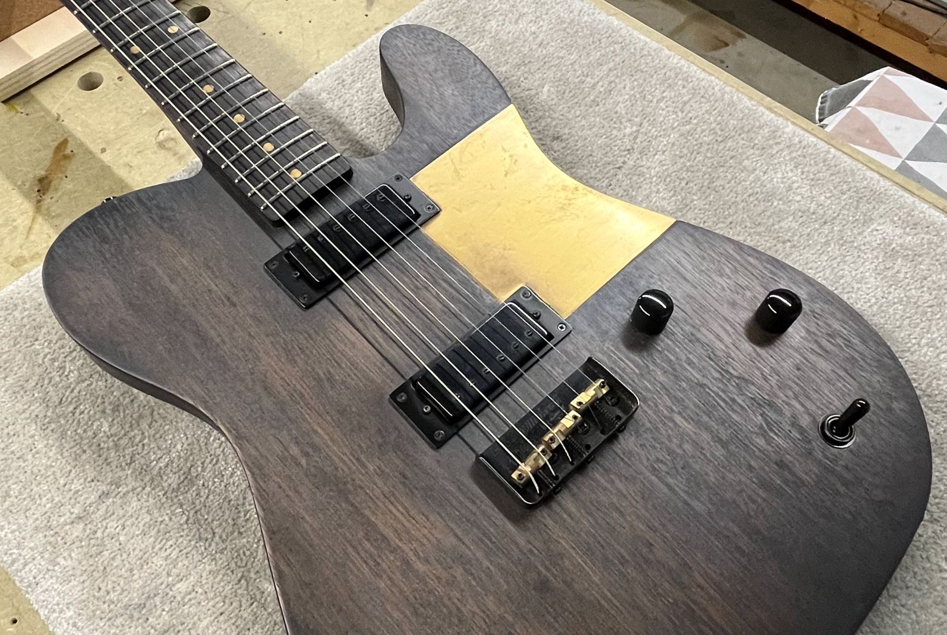 Een bruine elektrische gitaar ligt op een tafel.