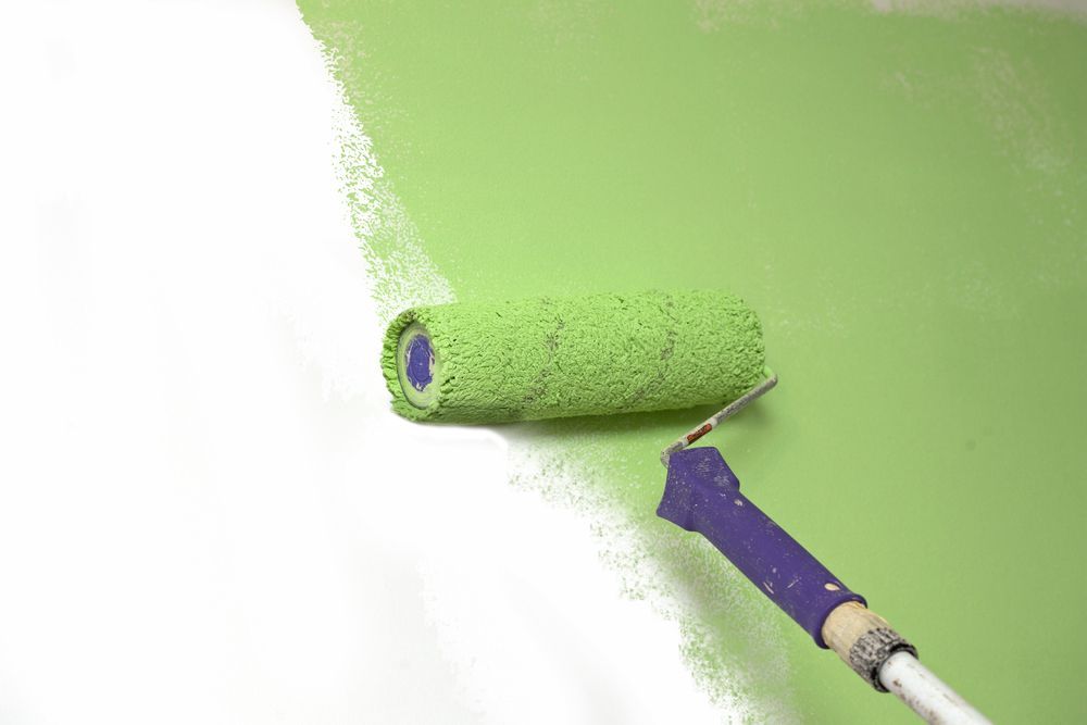 A Paint Roller Applies Green Paint to a White Wall — G.N Painting and Decorating in Bonny Hills, NSW