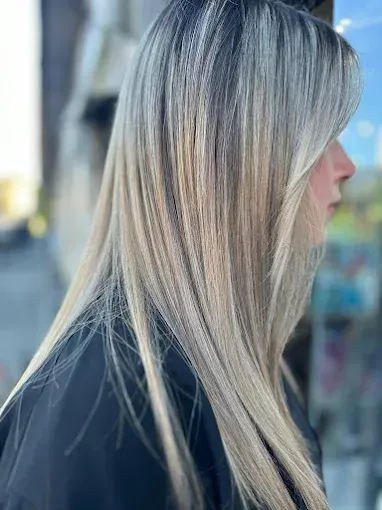 Donna con lunghi capelli biondi e castano chiaro scalati, vista di profilo laterale.