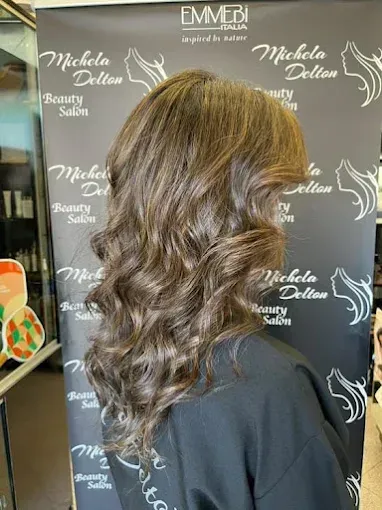 Donna con capelli castani ondulati, acconciata in un salone di bellezza.