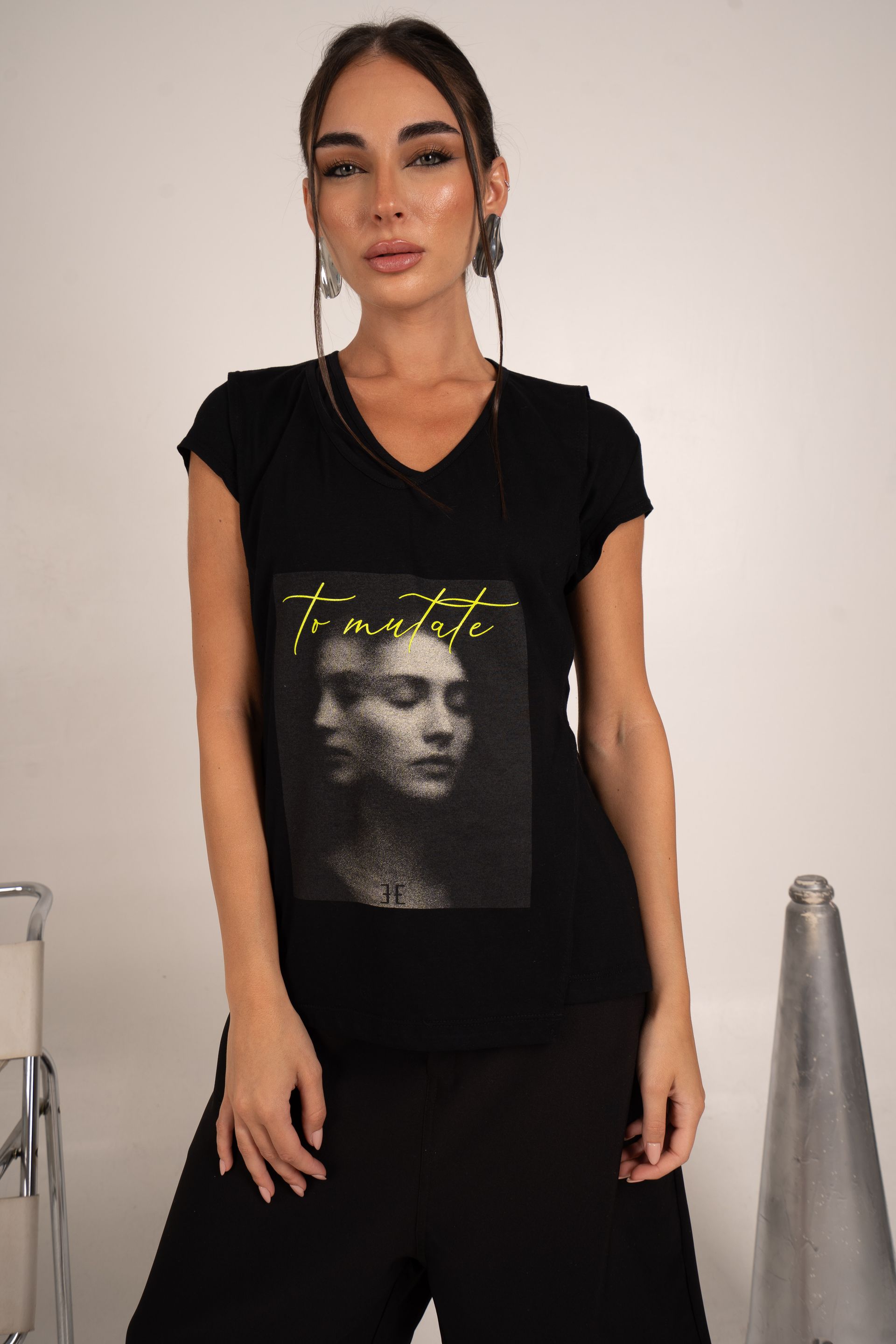 Mujer que lleva una camiseta negra con cuello en V con una imagen impresa de una cara y un texto.