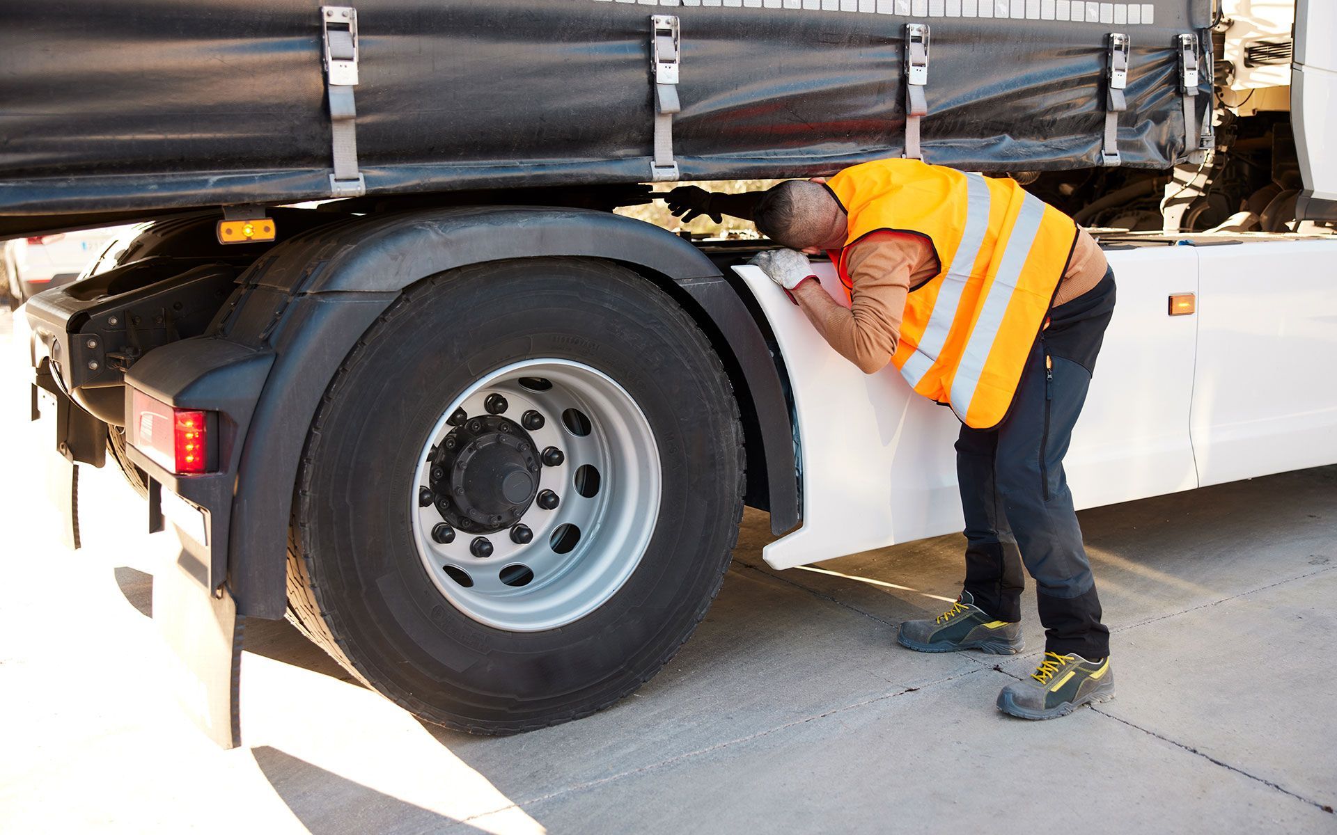 A man is looking at the side of a truck.