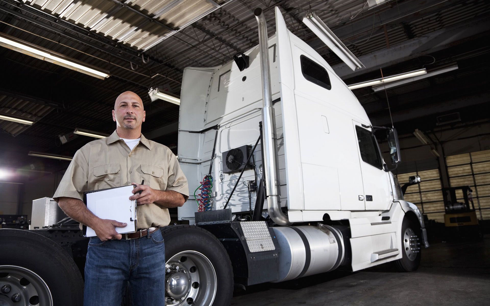 A man standing in front of a semi truck holding a clipboard