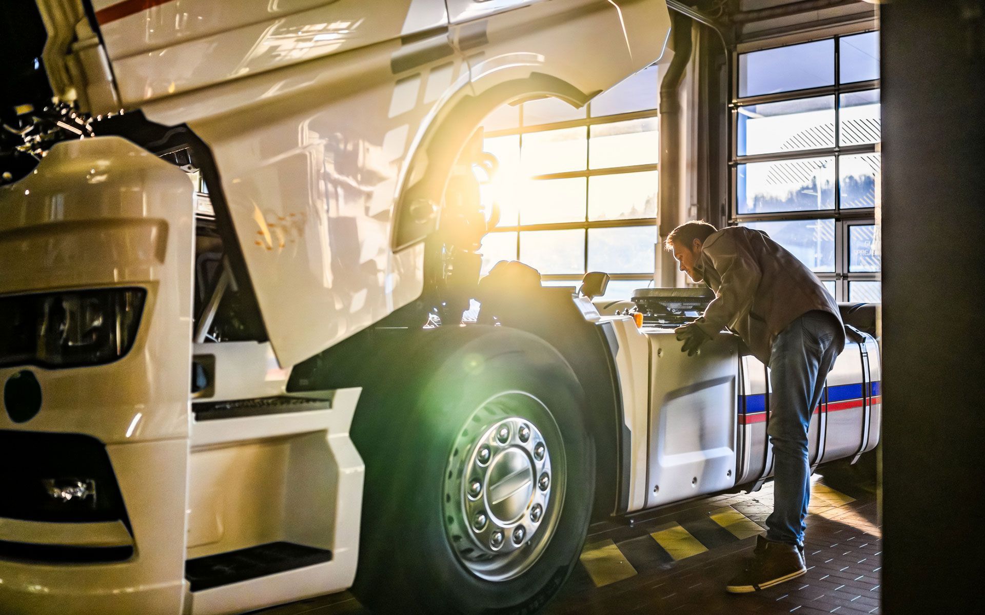 A man is working on a semi truck in a garage.