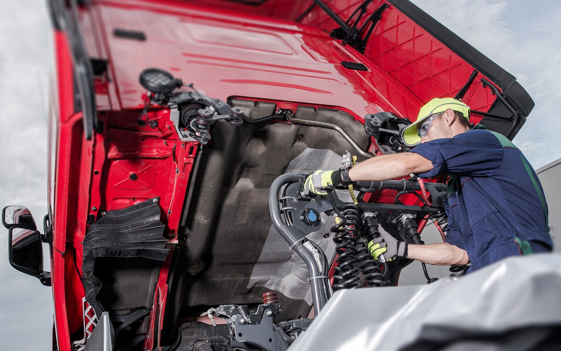 A man is working on the engine of a red truck.