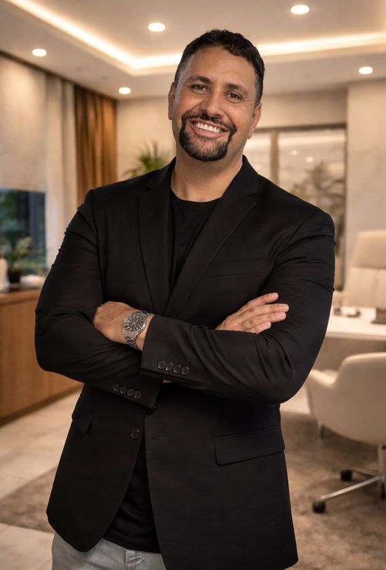 Retrato profissional do nutricionista Dr. Dhiego Ventura, sorrindo com os braços cruzados contra um fundo escuro e elegante.