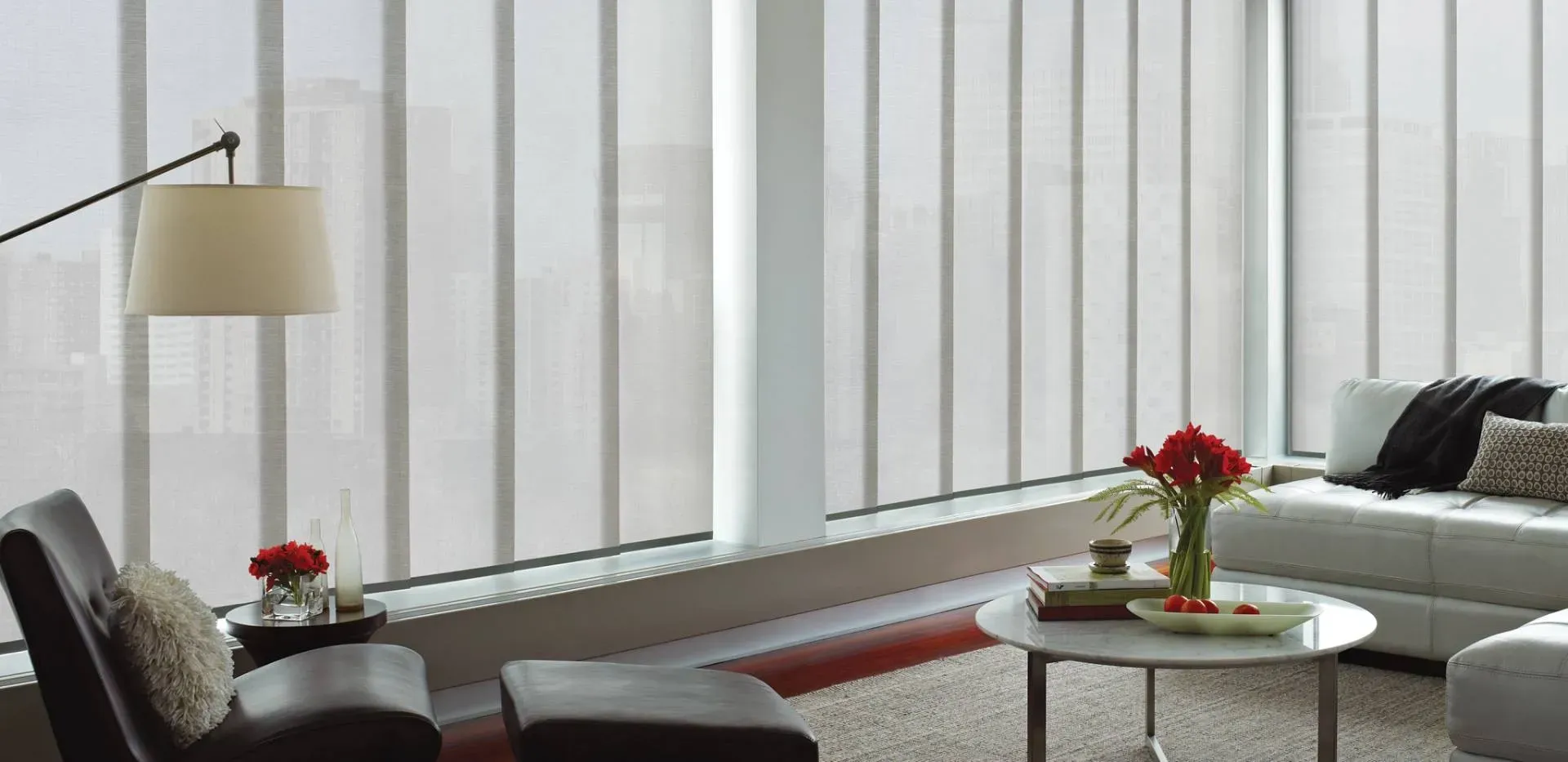 A modern living room with large panel blinds, a sofa, coffee table, and floor lamp.