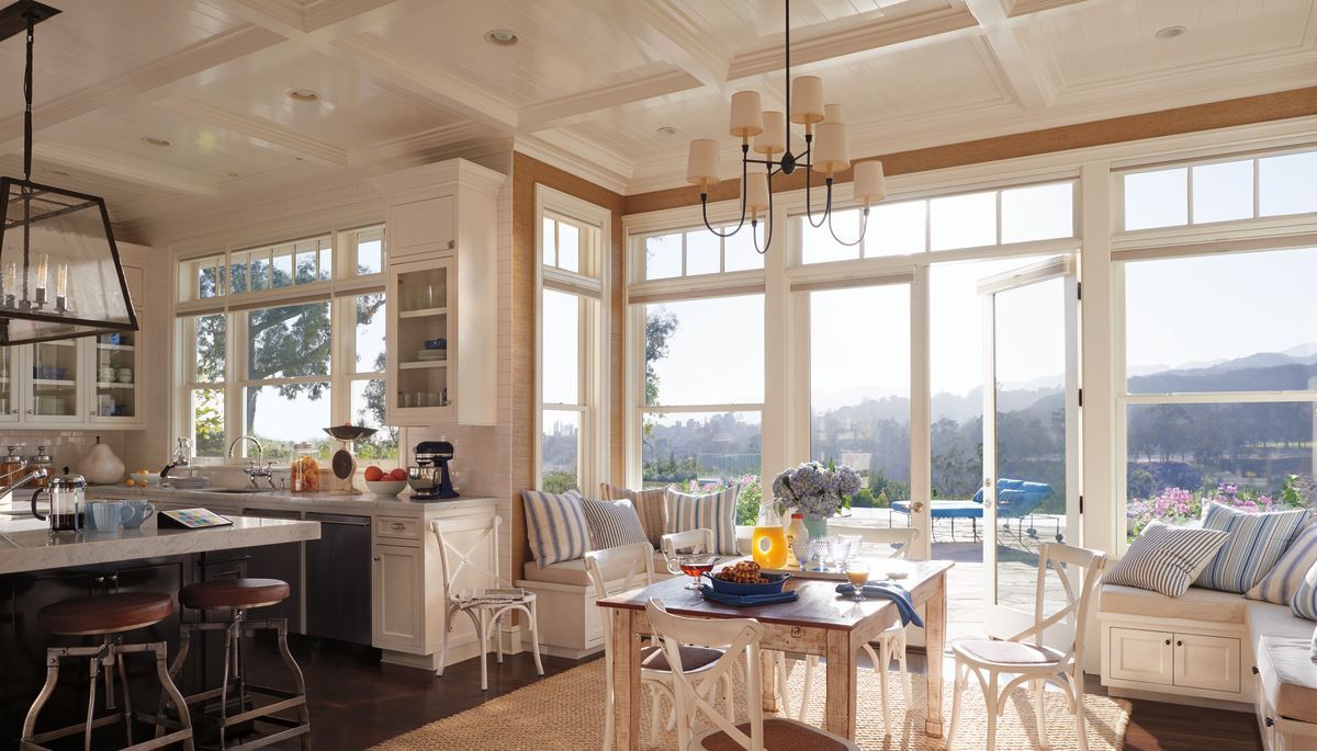 Bright kitchen with windows, table, chairs, and countertops. Exterior view of trees and water.