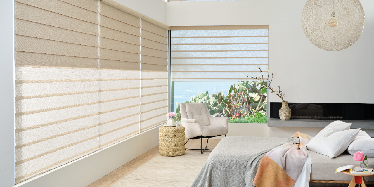 Bedroom with window shades, natural light, seating area, and neutral decor.