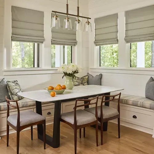 Dining area with a table, chairs, built-in bench seating, windows, and a hanging light fixture.