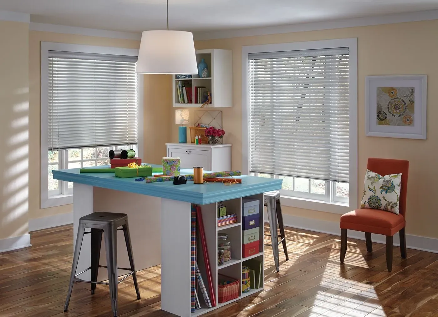 Craft room with craft table, storage, and windows with blinds; orange chair.