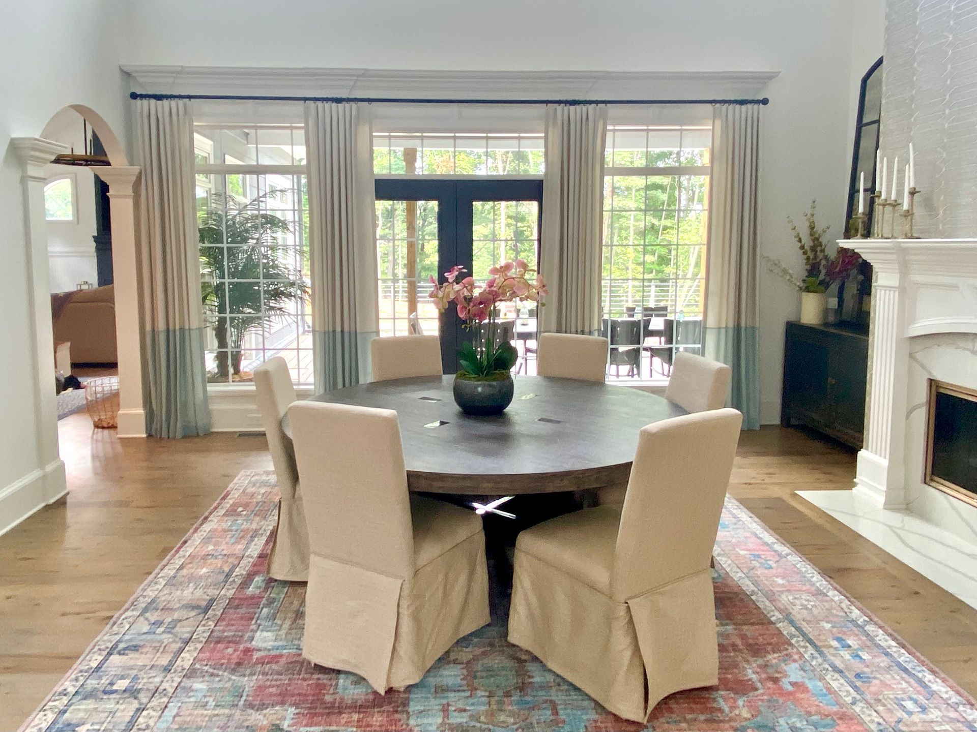 Dining room with a round table, upholstered chairs, area rug, windows, and a fireplace.