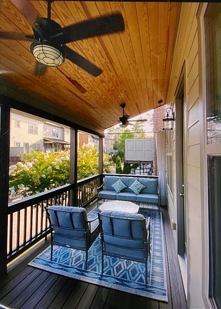 Covered porch with seating, rug, ceiling fans, and wood ceiling.