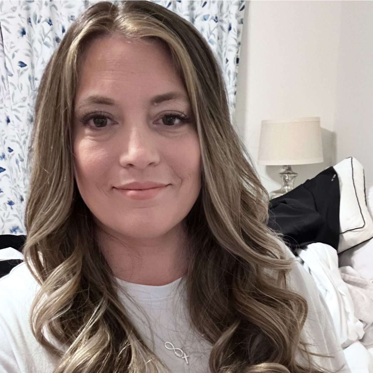 Woman seated in a green armchair, wearing black top and striped pants, in front of a table with fabric samples.