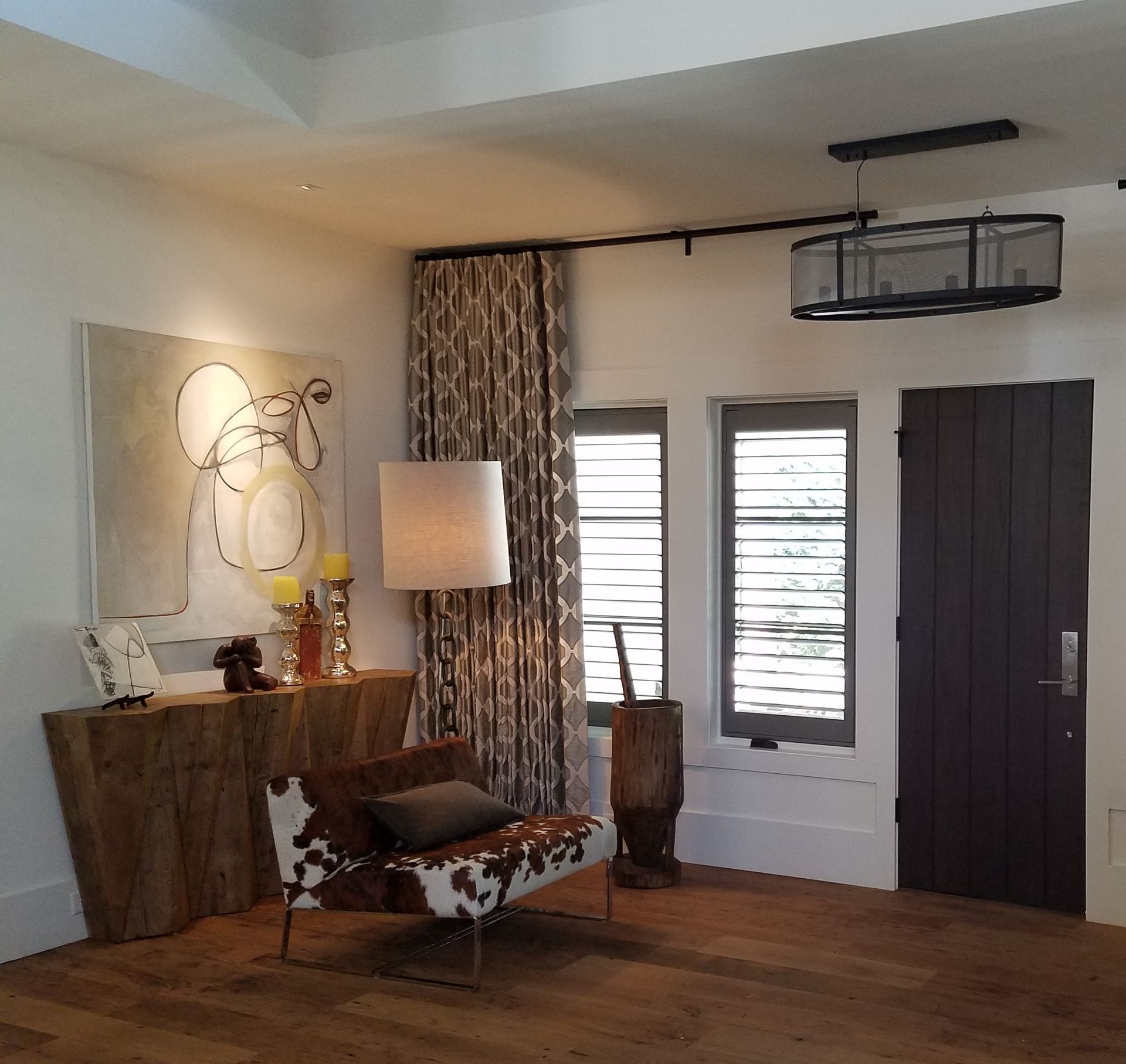 Living room with wood floors, artwork, accent chair, and dark door.