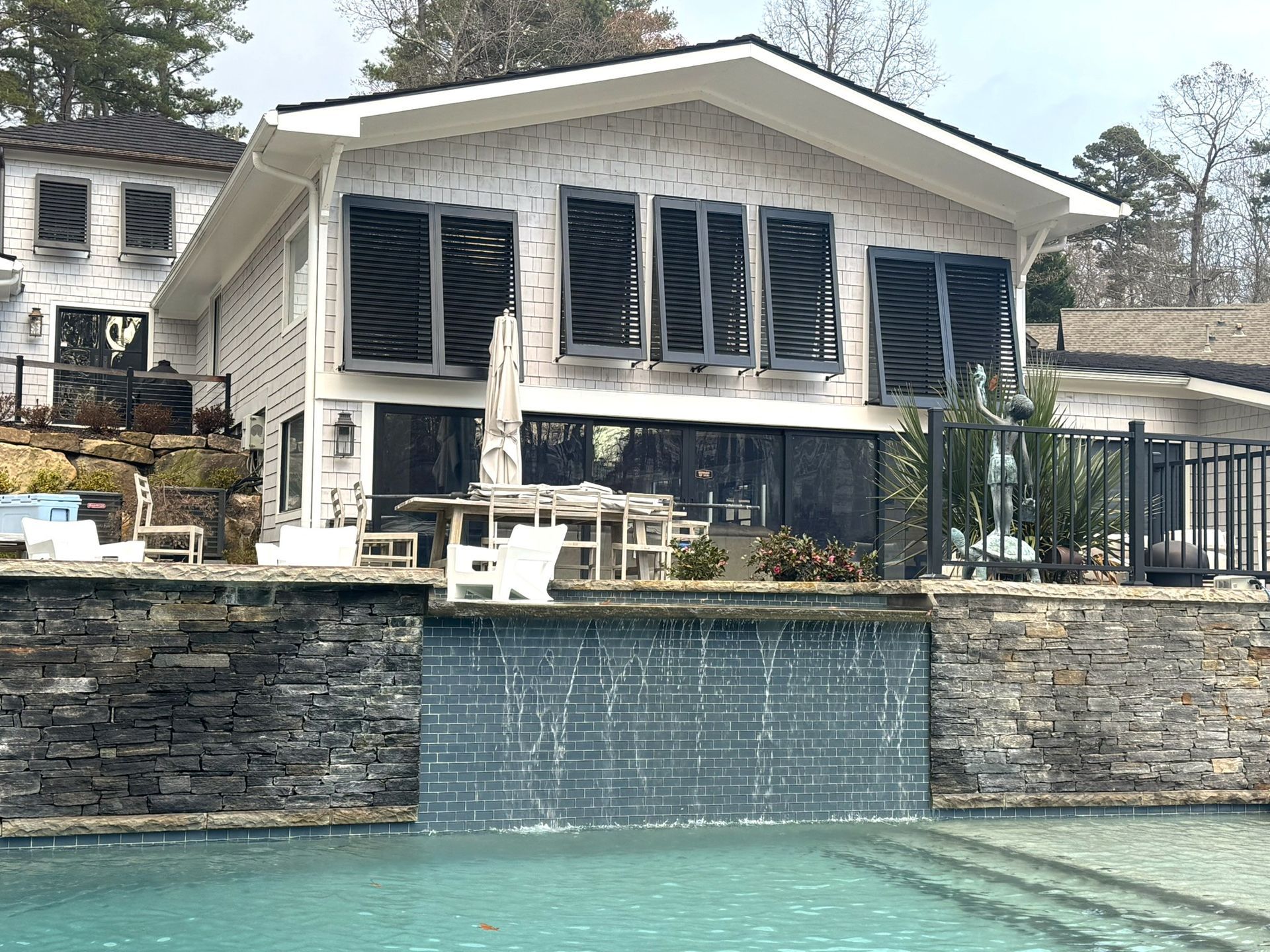 Modern white house with dark window frames, pool, and waterfall feature.