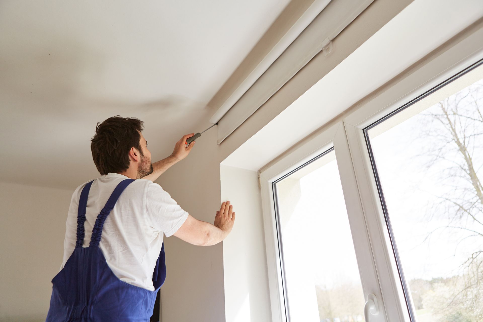 A professional installing a roller shade on a window
