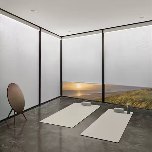 Yoga studio with mats, blocks, and a mirror, overlooking an ocean sunset.